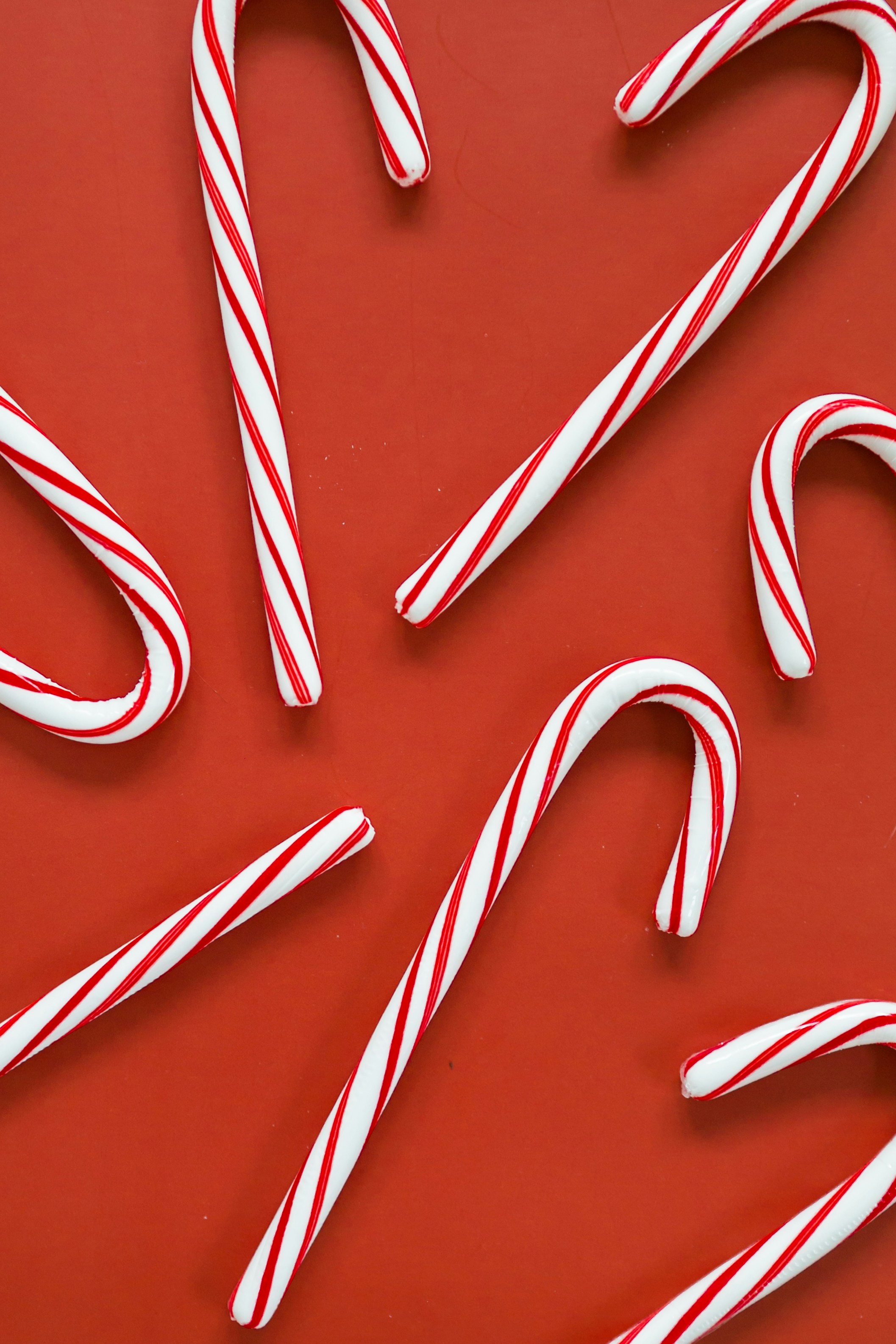 Candy canes spread out on a red background.