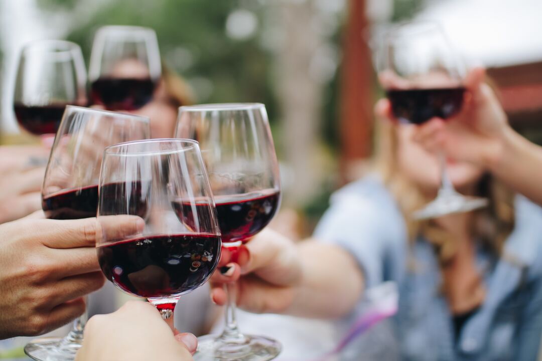 Multiple people bringing their wine glasses together.